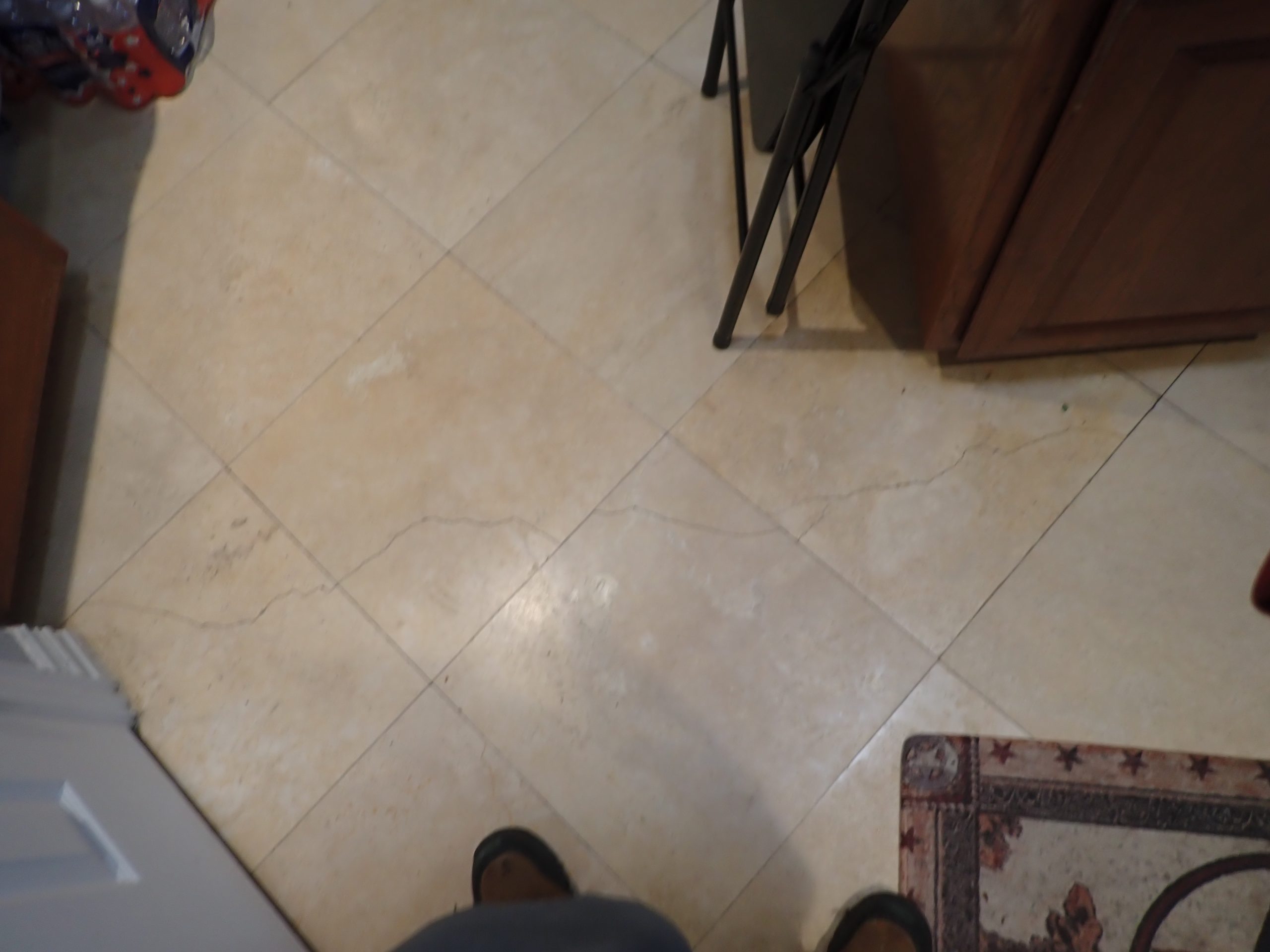 Crack running across stone tile flooring in a North Texas home, one possible sign of differential foundation movement